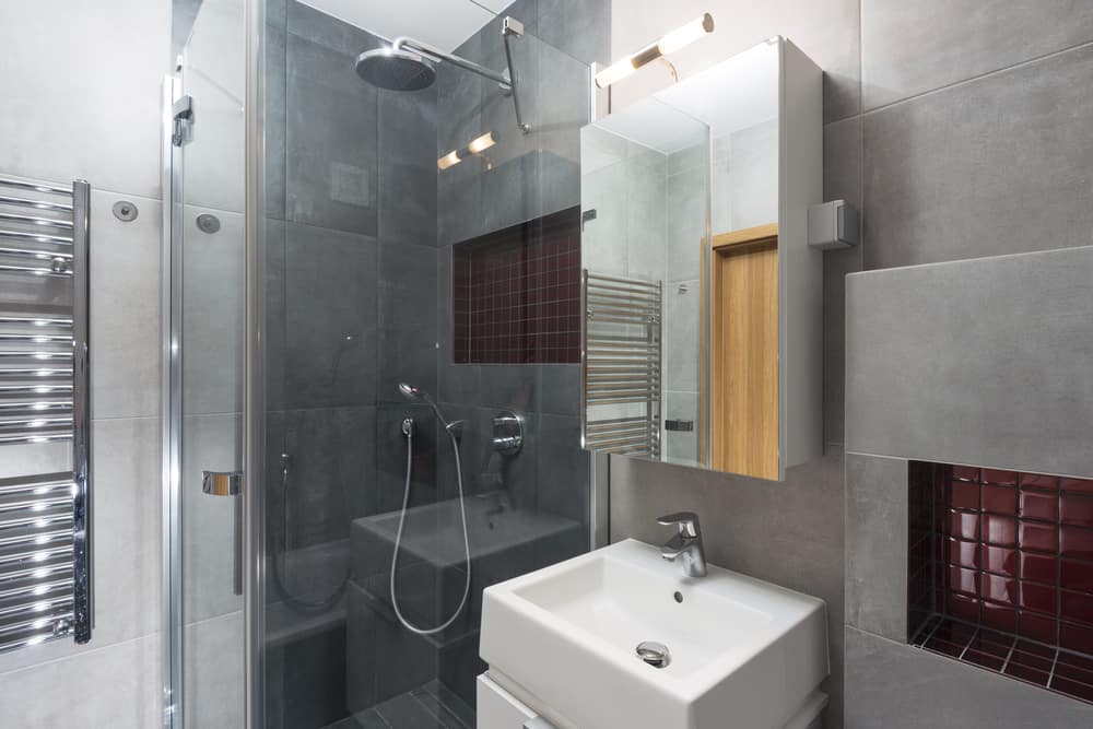 gray slate tile bathroom with corner shower and white vanity 