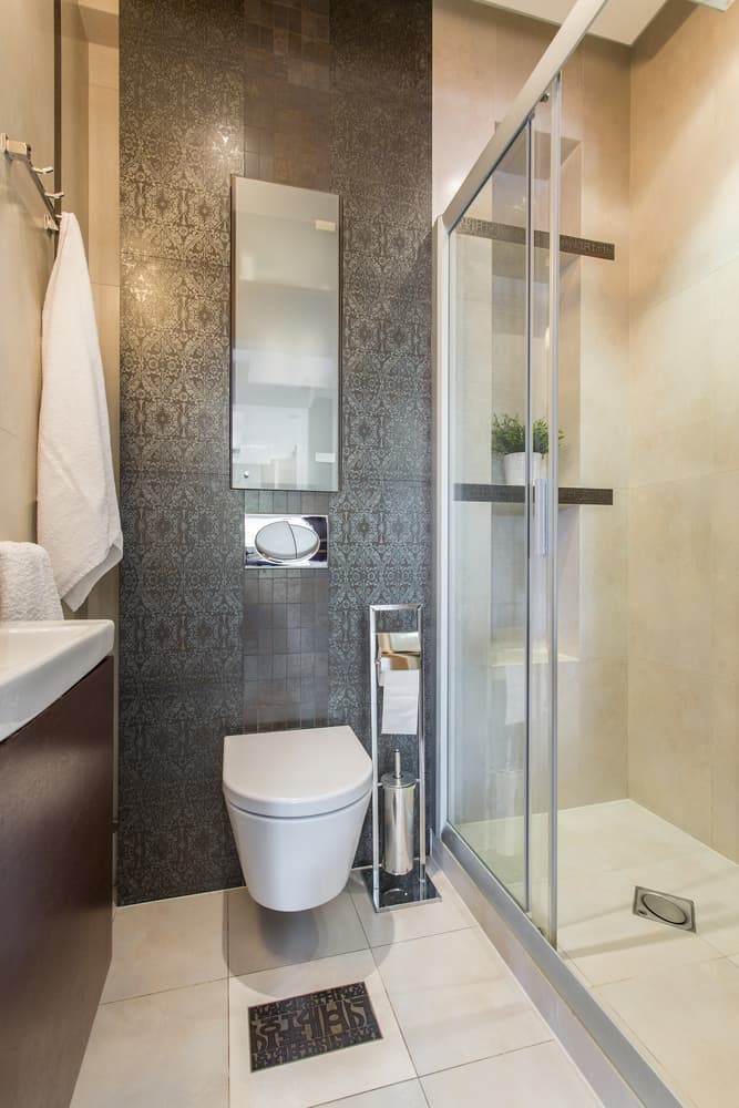 Small modern bathroom with dark accent wall, floating toilet, and glass-enclosed shower.