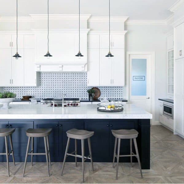 Modern kitchen with black and white cabinetry, marble countertops, small black pendant lights, and stylish wooden stools