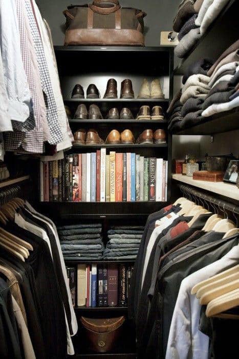 Organized closet with clothes, shoes, books, and a leather bag on top