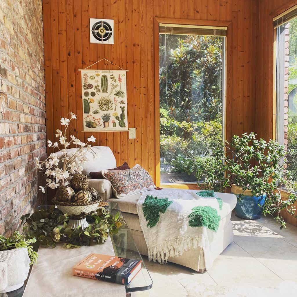 Cozy sunroom with brick wall, wood paneling, chaise lounge, potted plants, and decor accents.