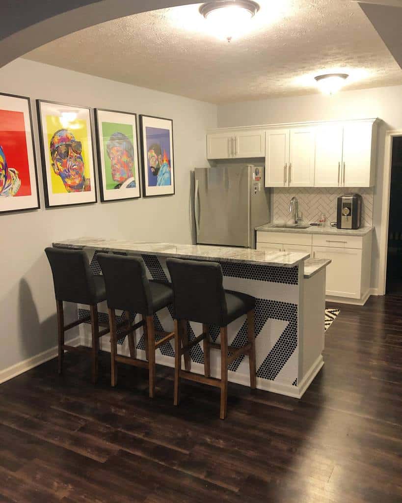 Modern wet bar featuring sleek white cabinets, marble countertops, and vibrant pop art decor for a lively ambiance.