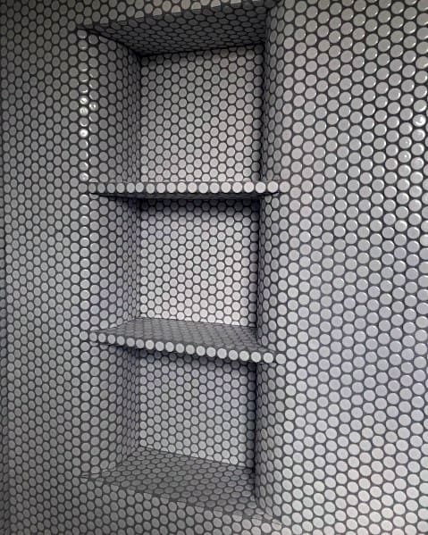 Recessed bathroom shelves with small round grey tiles in a mosaic pattern.