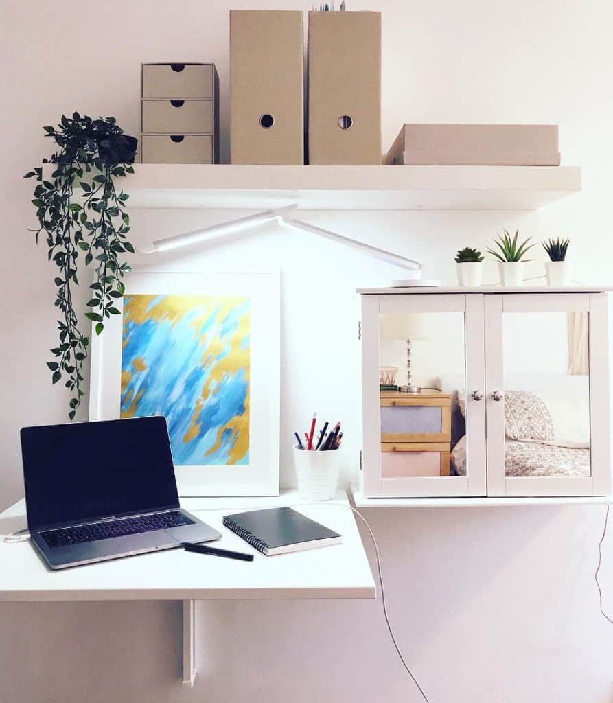 Small home office setup with wall-mounted desk, storage, and plants.