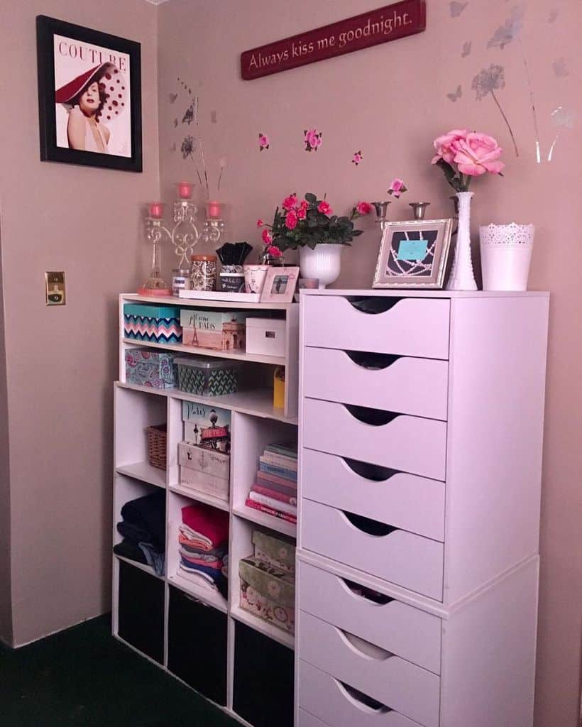 Bedroom corner with pink storage drawers, shelves, and decorative accents.