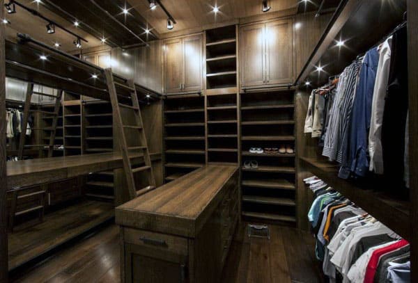 Luxurious walk-in closet with wooden shelves, a central island, shirts hung neatly, and a sliding ladder