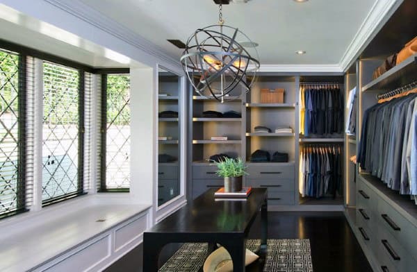 Modern walk-in closet with shelves of clothes, a central table with a plant, and a decorative light fixture