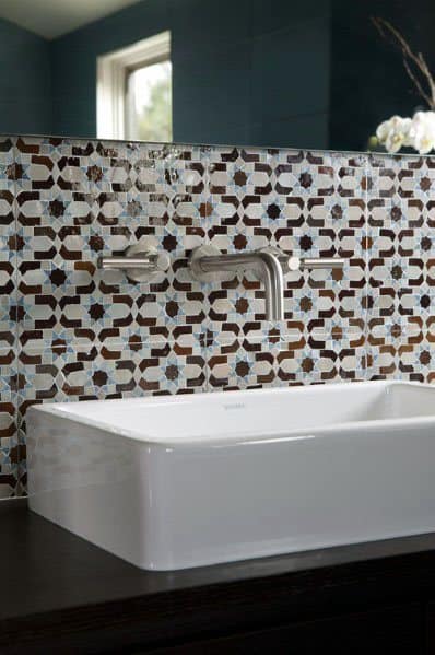 Decorative star-patterned tile backsplash with wall-mounted faucet and white rectangular sink.