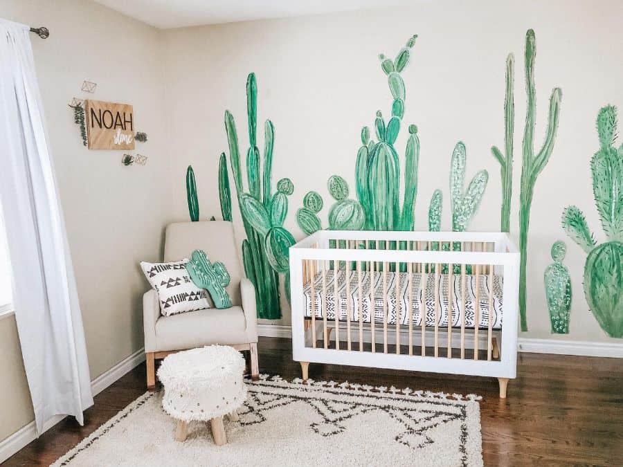 Baby room with cactus mural, white crib, cozy chair, and textured rug.