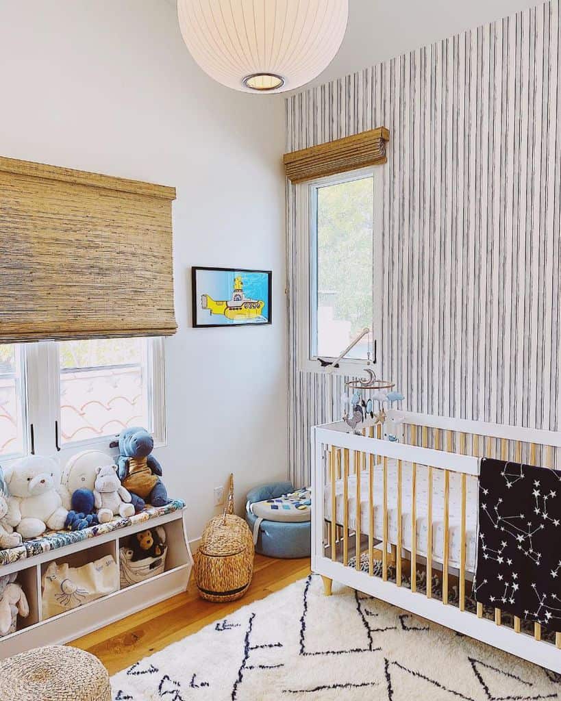 Baby room with white crib, Yellow Submarine wall art, wooden blinds, and cozy stuffed animal nook.