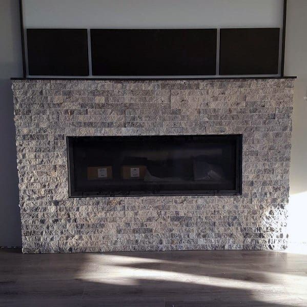 A modern fireplace surrounded by rugged grey stone tiles, blending contemporary and rustic styles.