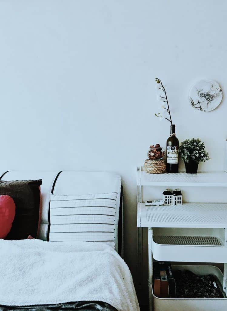 Bedside storage cart with decor items and cozy pillows.