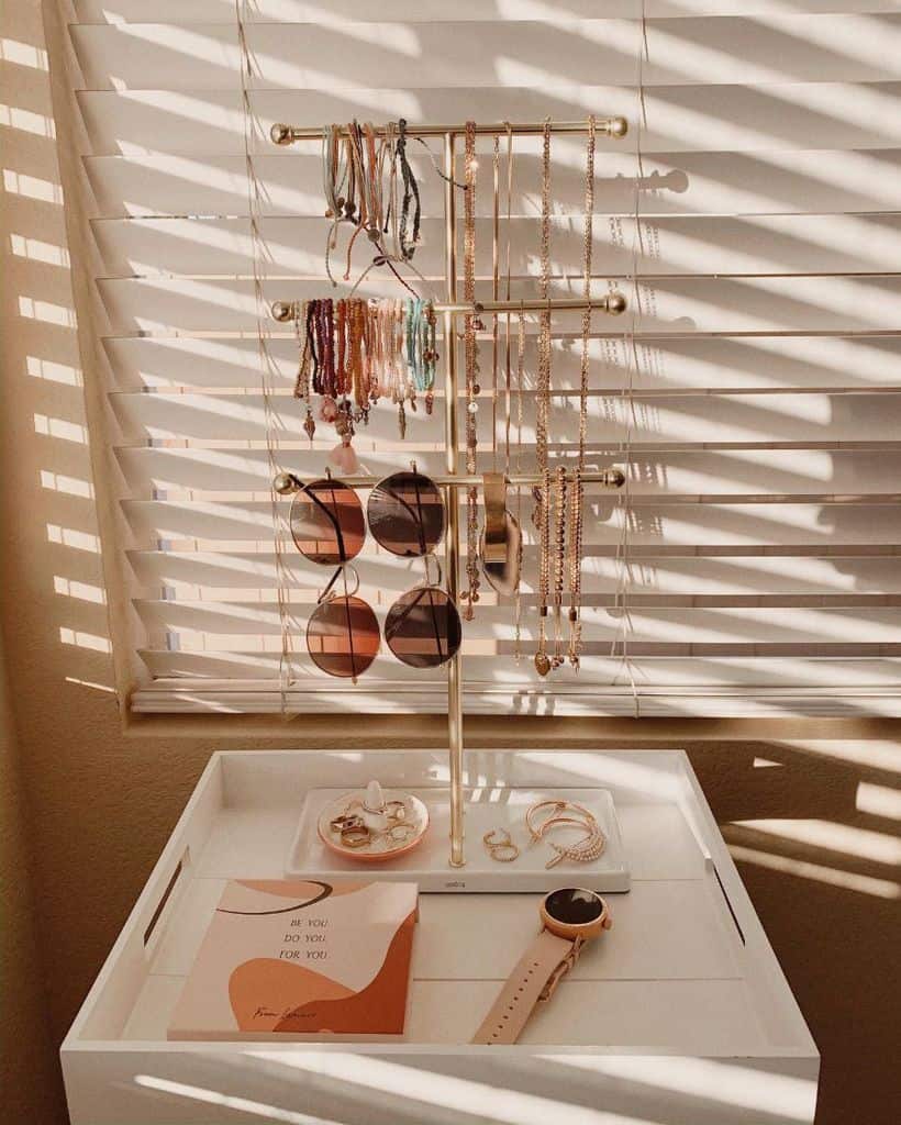 Gold jewelry and accessory stand with bracelets, necklaces, and sunglasses.