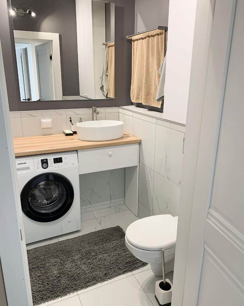 Compact bathroom with tile walls, wood countertop, and built-in washing machine.