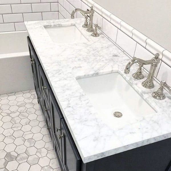 Bathroom with white beveled subway tile backsplash, marble countertop, and hexagon floor tiles.