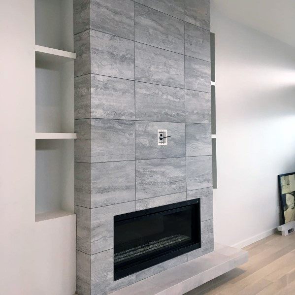 Contemporary fireplace with gray textured tiles, black gas insert, and built-in shelving.