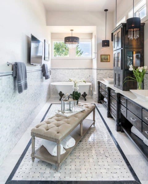 Contemporary bathroom with mounted TV, freestanding tub, and tufted bench in the center.