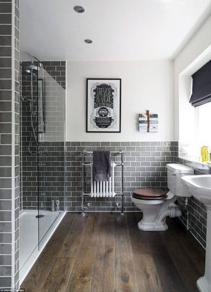 small modern shower with gray tiles and wood floor 