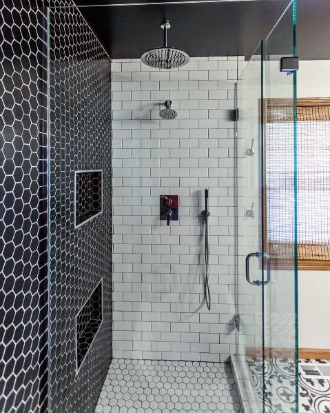 Modern shower with black hexagon tiles, white subway tiles, rain showerhead, and glass door.