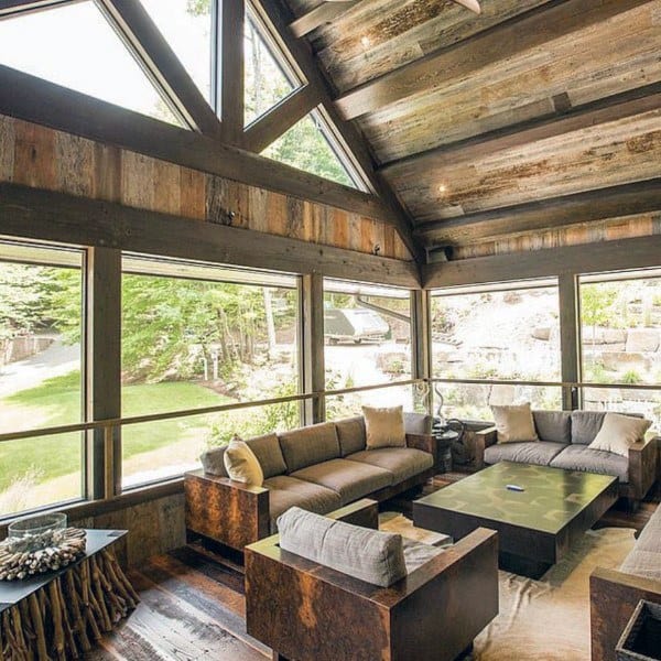 Rustic sunroom with reclaimed wood ceiling, large windows, and modern cozy seating area.