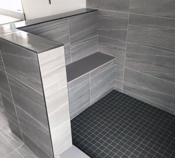 Grey tiled shower with a built-in bench and dark floor tiles