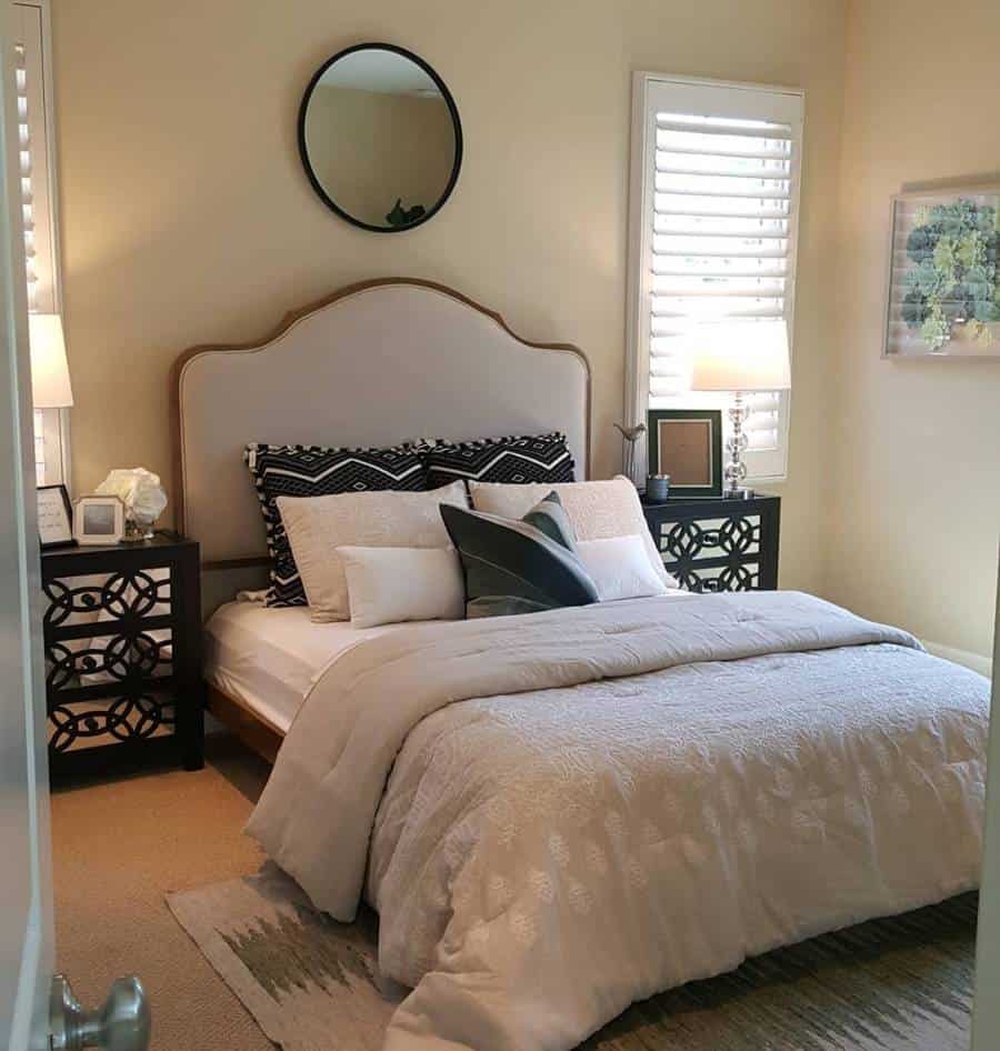 Contemporary bedroom with large upholstered bed, decorative pillows, and black nightstands.