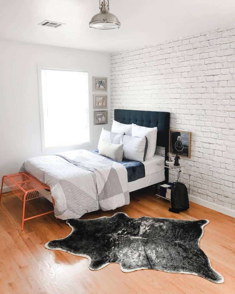 Modern bedroom with white brick wall, cowhide rug, and geometric bedding design.