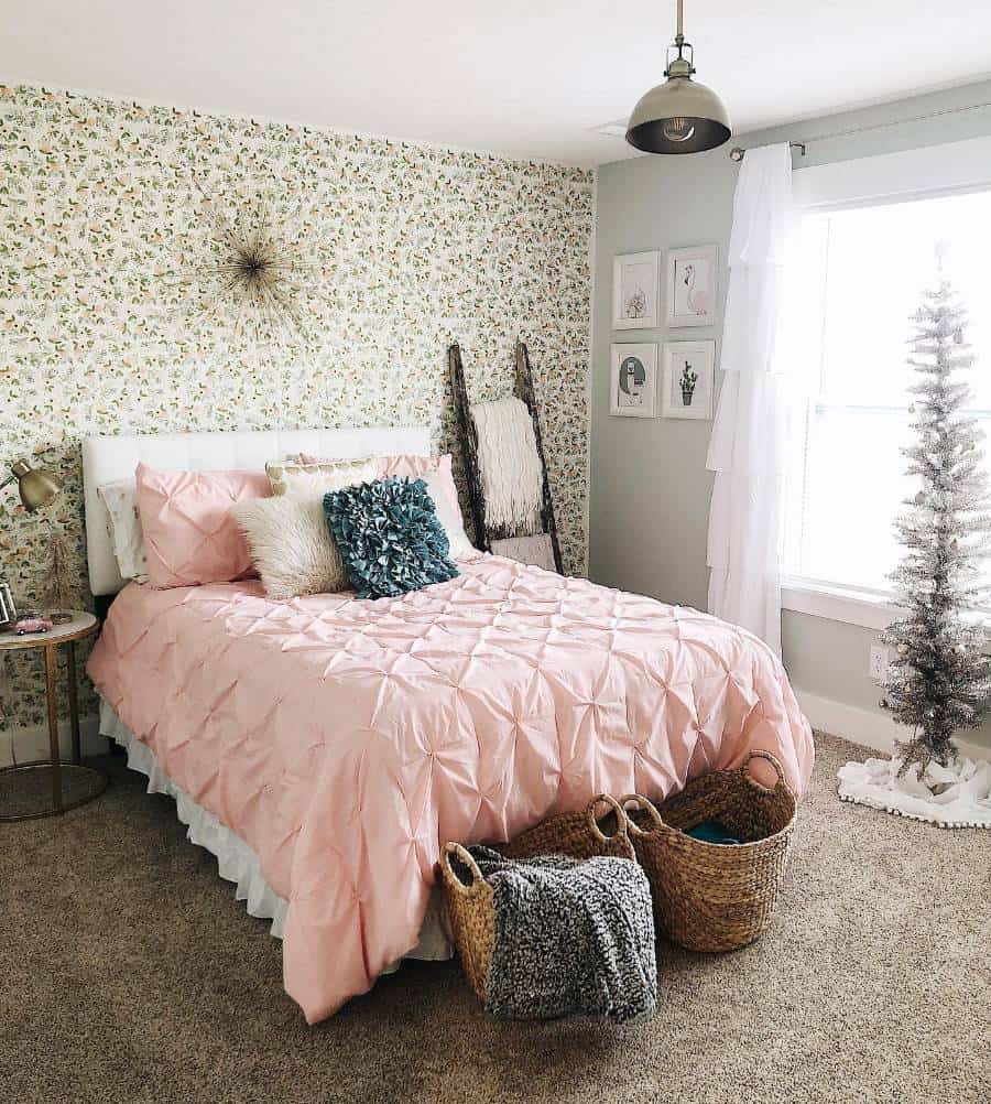 Bedroom with floral wallpaper, pink duvet, wicker baskets, and a small Christmas tree.