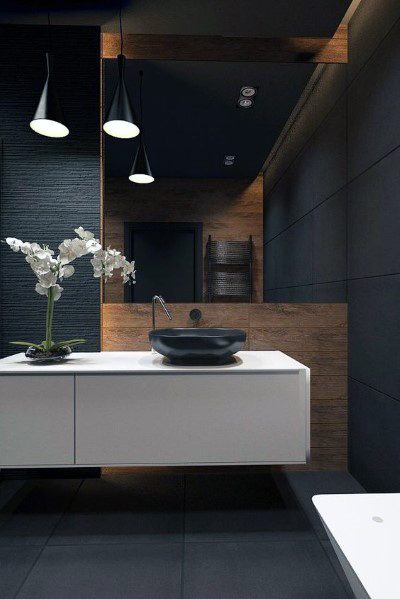 Sleek modern bathroom with black vessel sink, hanging lights, and wood accent wall.