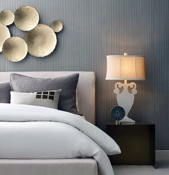 Modern bedroom with textured wall, gold circular wall art, and elegant bedside lamp.