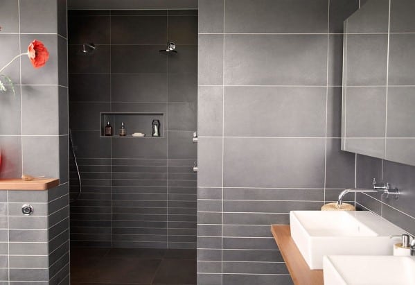 Modern bathroom with gray tiles, walk-in shower, and double sinks on a wooden counter