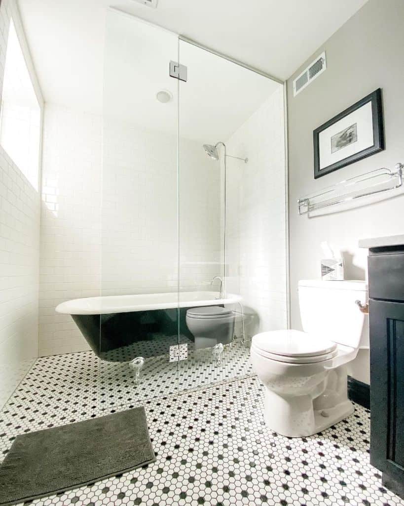 Country-style black and white bathroom with clawfoot tub, glass enclosure, and hexagon tile floor.