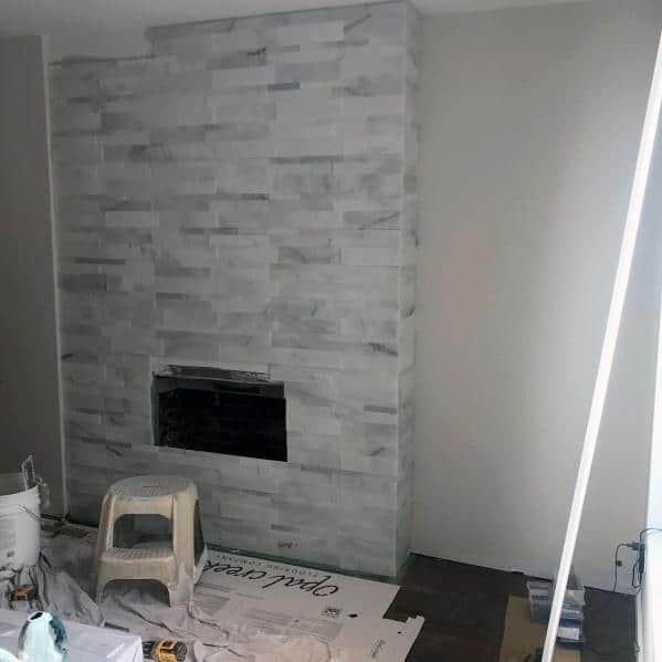 Floor-to-ceiling gray stacked stone fireplace in a modern living room under renovation.