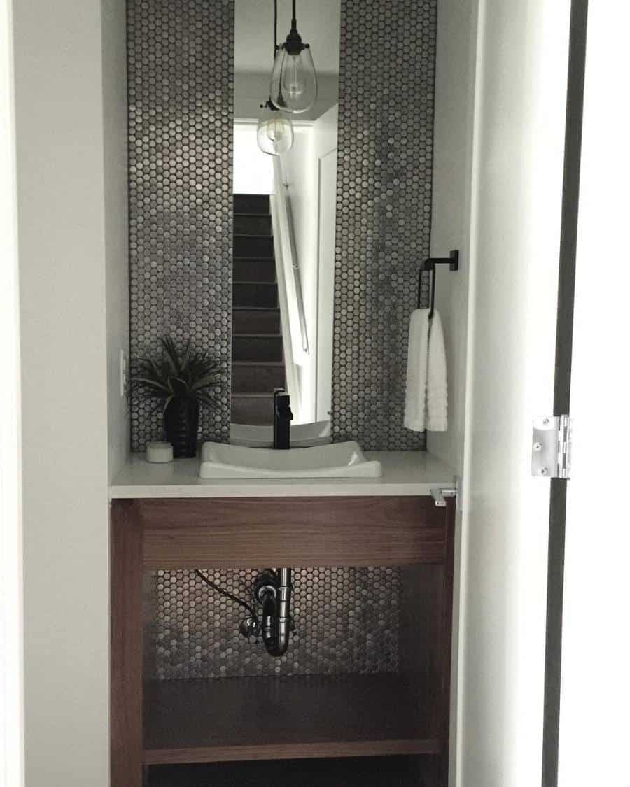 Small modern bathroom with hexagonal accent wall, a white sink, black faucet, and a pendant light above