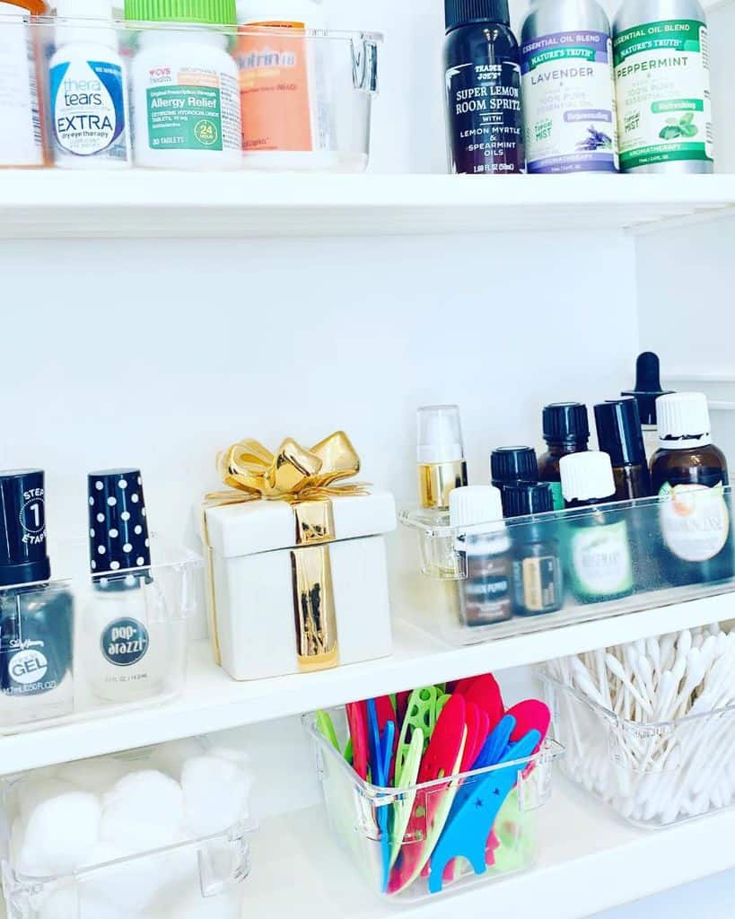 Bathroom medicine cabinet with essential oils, nail polish, and cotton swabs.