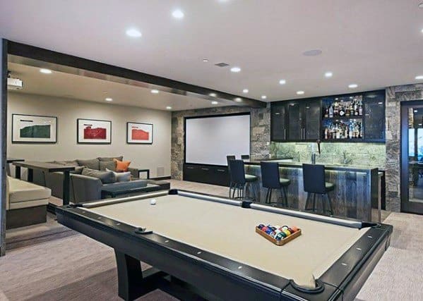 Modern mancave with pool table, stylish bar, large sectional sofa, and built-in projector screen.