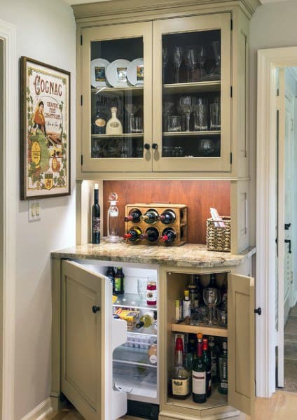 Traditional mini bar with cream cabinets, wine rack, mini fridge, and granite countertop.