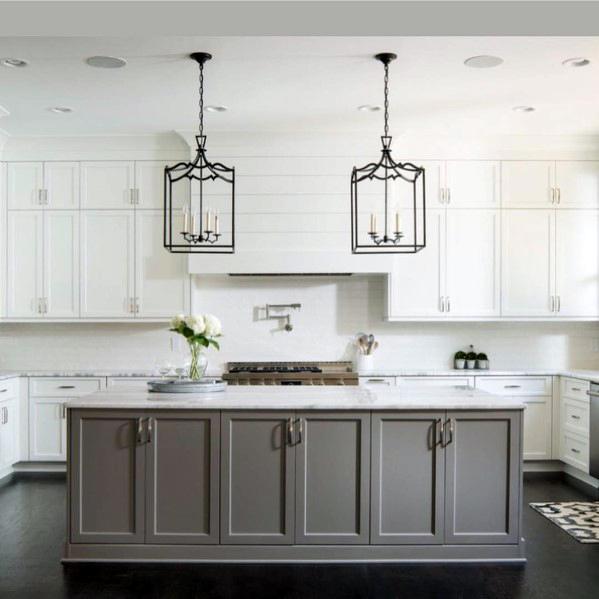 Two elegant black lantern-style chandeliers hang over a gray and white kitchen island, creating a refined and stylish atmosphere