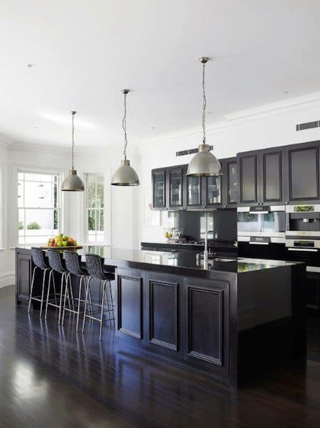 Traditional black kitchen cabinets with a large island, pendant lighting, and bar stools.