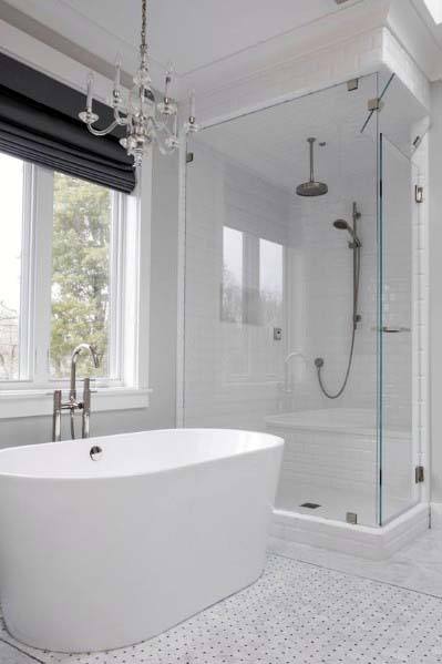 Minimalist bathroom with a white freestanding tub, glass shower enclosure, and chandelier under natural light