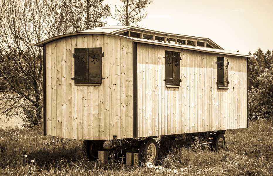 Vintage-style trailer shed with wooden exterior and decorative shutters on windows.