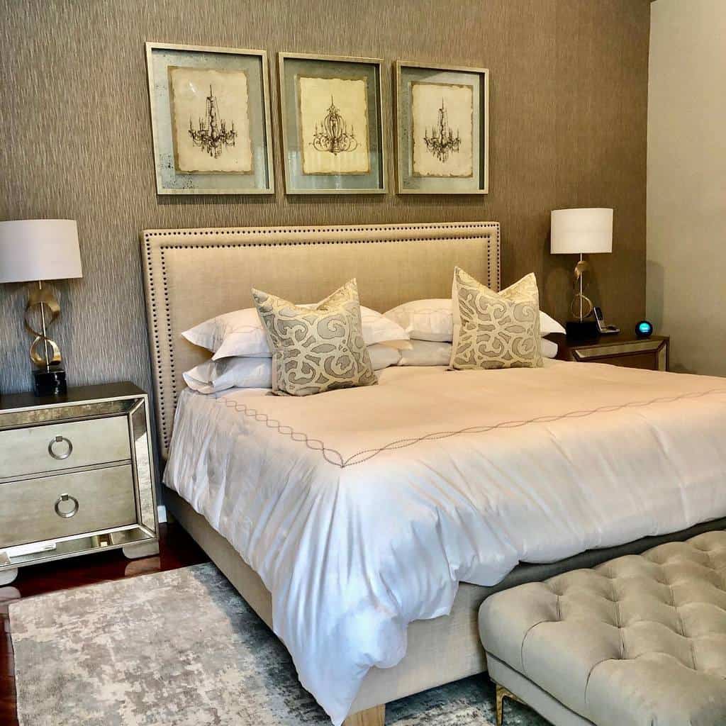 Elegant bedroom with textured walls, framed chandelier art, and mirrored bedside tables.