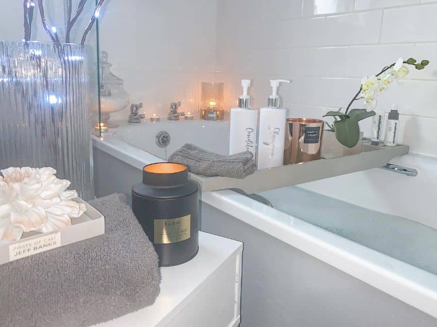 Relaxing bathtub setup with candles, soap dispensers, and a tray holding bath essentials.