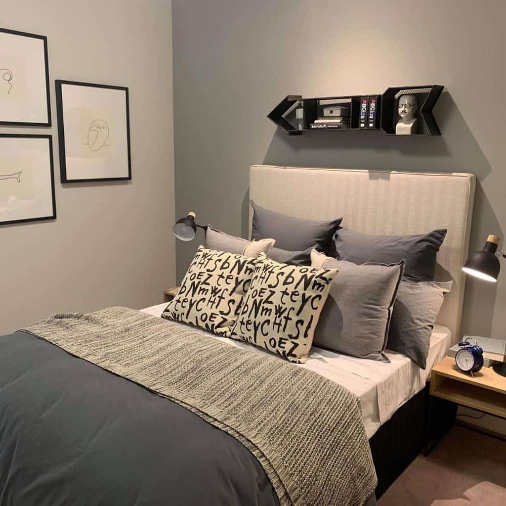 Small modern bedroom with arrow wall shelf, abstract art, and cozy bedding in gray tones.