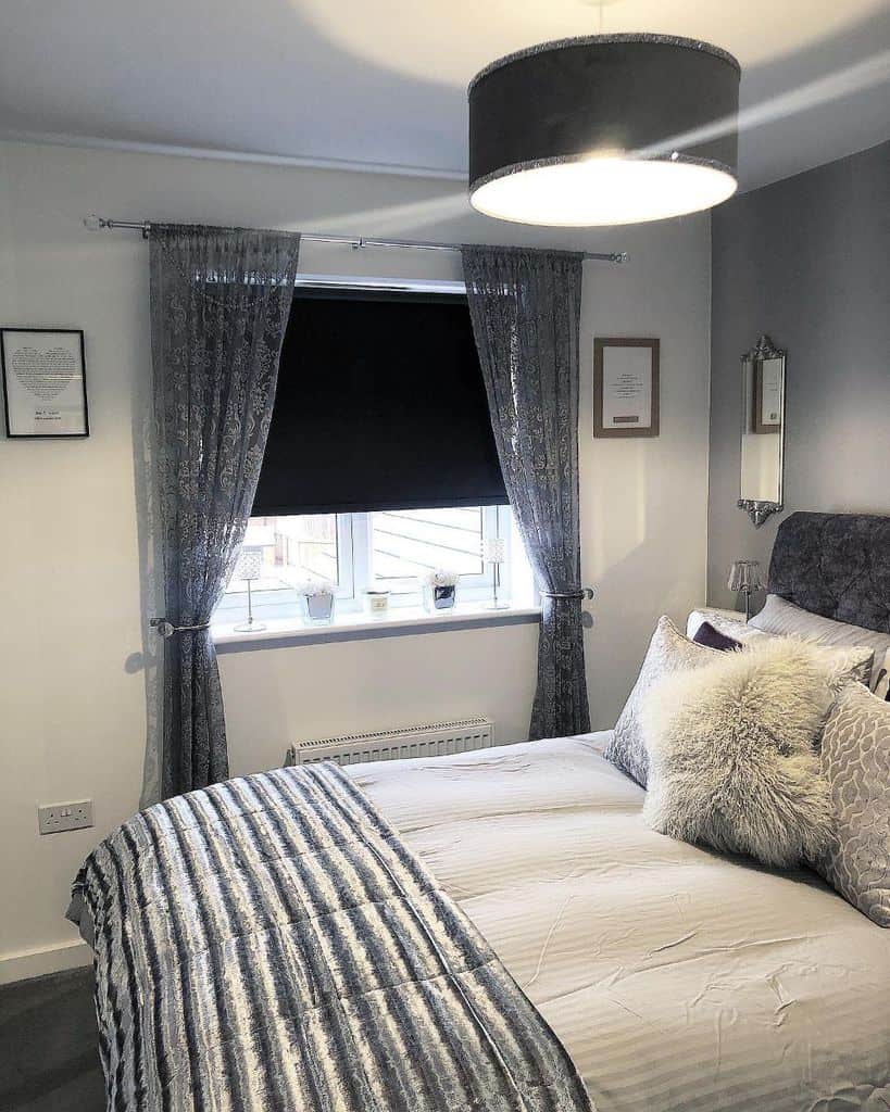 Elegant bedroom with gray curtains, plush bedding, and a black drum ceiling light.