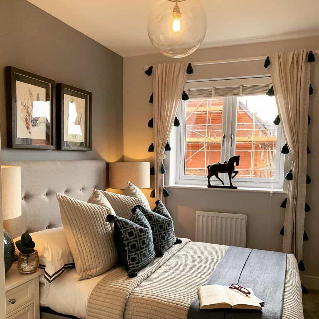 Modern bedroom with tufted headboard, horse statue, framed artwork, and tassel curtains.