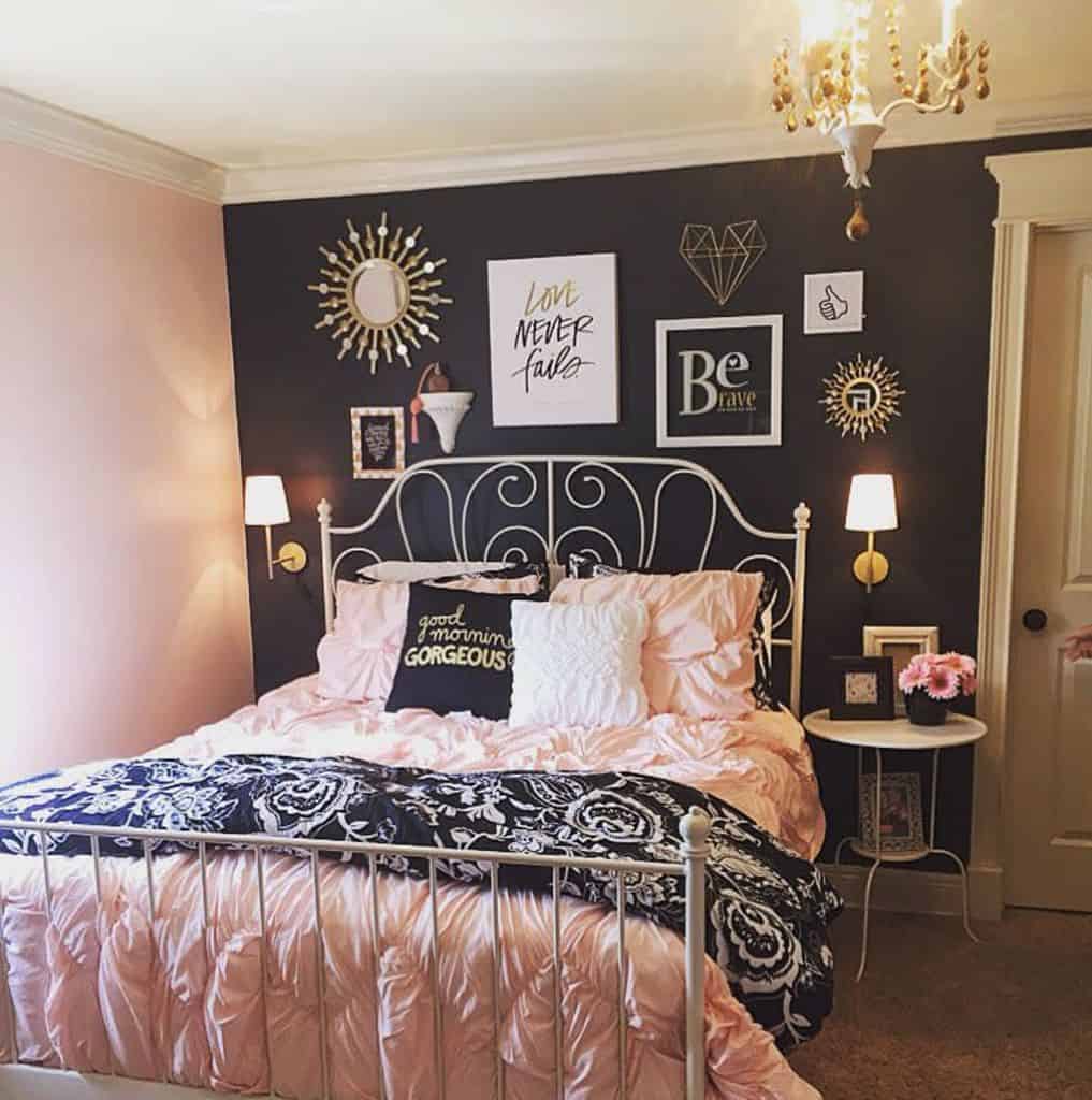 Two-tone pink and gray bedroom with four-poster bed, positive wall art, and chandelier lighting.