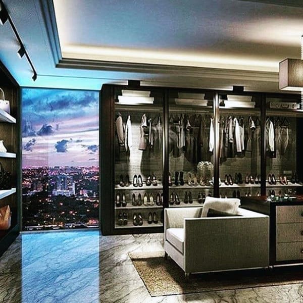 Luxurious walk-in closet with city skyline view, featuring clothing racks, shoe shelves, and seating area