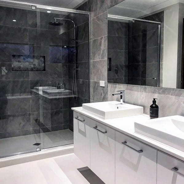 Modern grey bathroom with a sleek shower, dual sinks, and large mirror