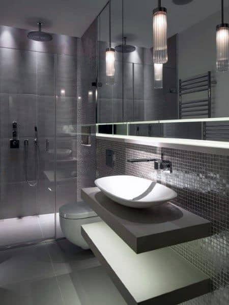 Ultra-modern grey bathroom featuring a floating vanity, illuminated shelving, and a glass-enclosed shower.